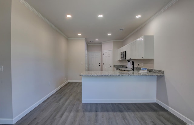 kitchen featuring kitchen peninsula, light stone countertops, light hardwood / wood-style floors, and white cabinets