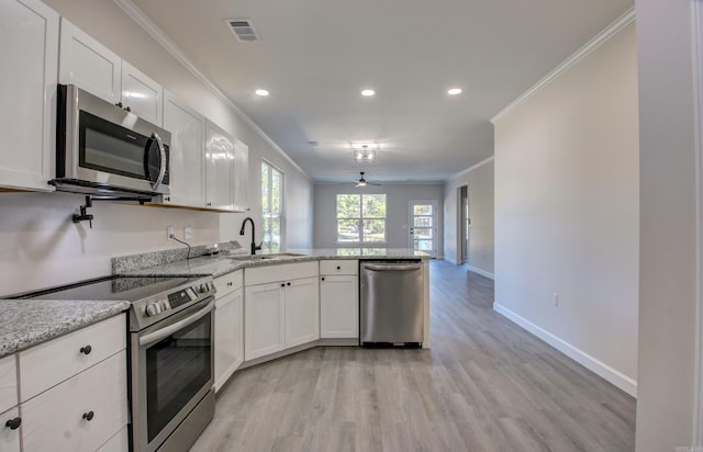 kitchen with white cabinets, ornamental molding, appliances with stainless steel finishes, and kitchen peninsula