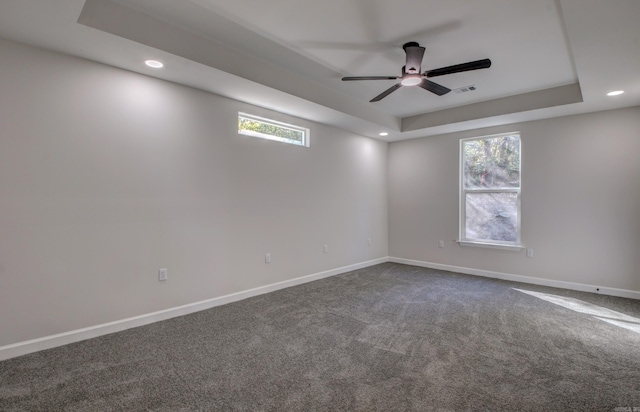 carpeted spare room with a tray ceiling and ceiling fan