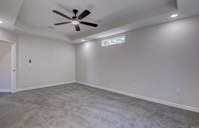 carpeted spare room with ceiling fan and a raised ceiling