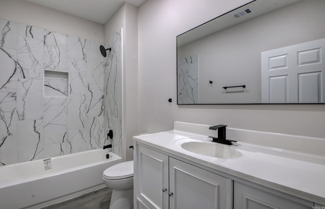 full bathroom featuring tiled shower / bath, vanity, hardwood / wood-style floors, and toilet