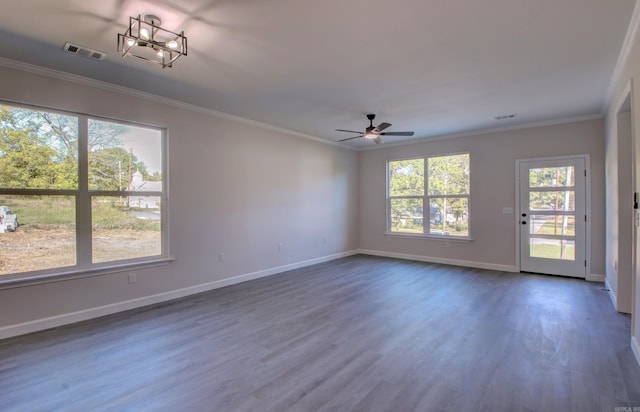 empty room featuring dark wood-type flooring, plenty of natural light, ornamental molding, and ceiling fan