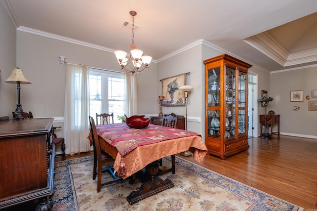 dining room featuring ornamental molding, hardwood / wood-style flooring, and a chandelier