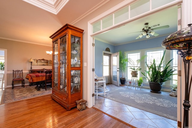 foyer entrance with ceiling fan, light wood-type flooring, and crown molding