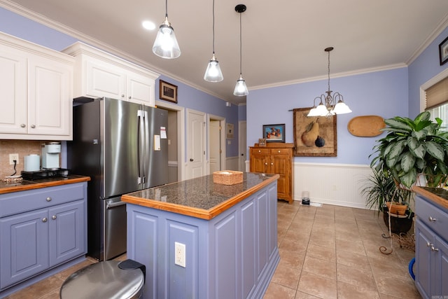 kitchen with a center island, stainless steel refrigerator, crown molding, hanging light fixtures, and white cabinetry