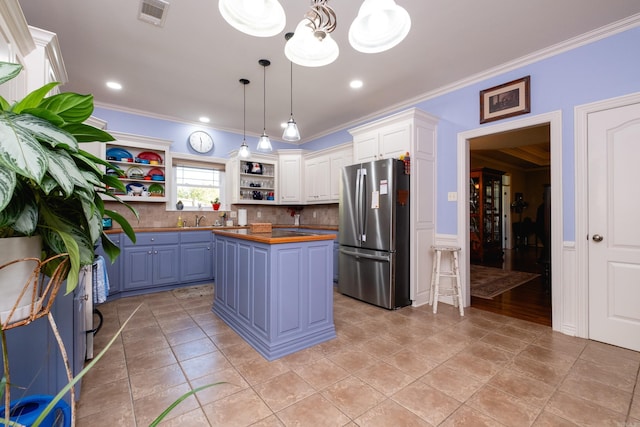 kitchen with stainless steel fridge, pendant lighting, wood counters, white cabinets, and a center island