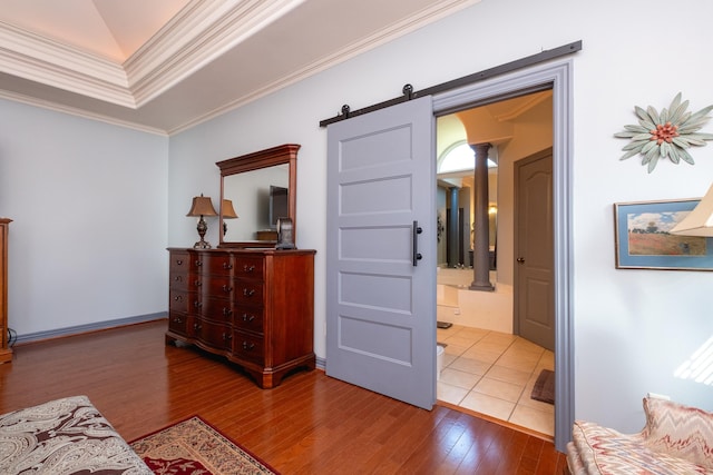 hall featuring ornate columns, crown molding, a barn door, and hardwood / wood-style floors