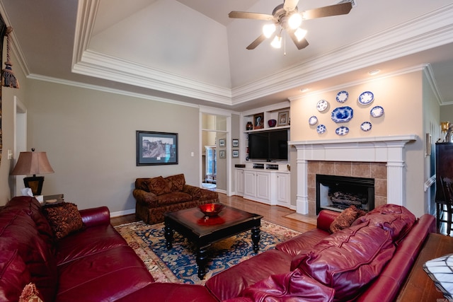 living room with ornamental molding, hardwood / wood-style flooring, built in shelves, and a tile fireplace