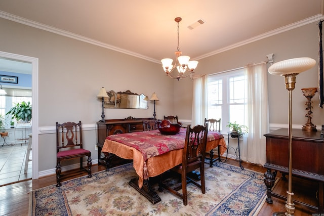 dining area with crown molding, hardwood / wood-style floors, and a notable chandelier