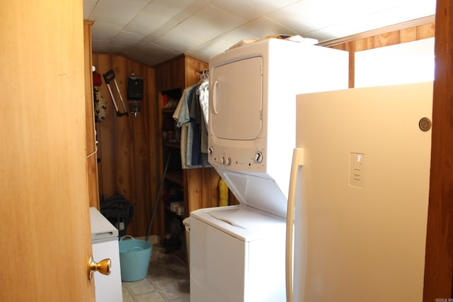 clothes washing area with wood walls and stacked washer and dryer