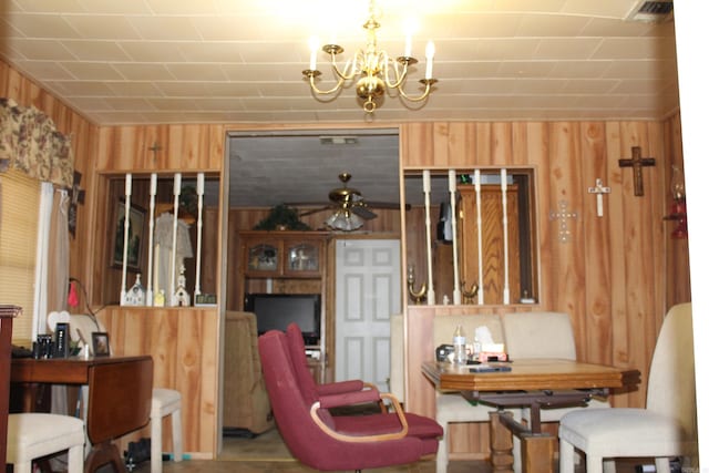 dining room with ceiling fan with notable chandelier and wood walls