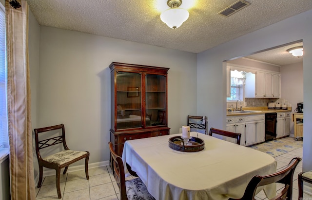 dining area with sink, light tile patterned floors, and a textured ceiling