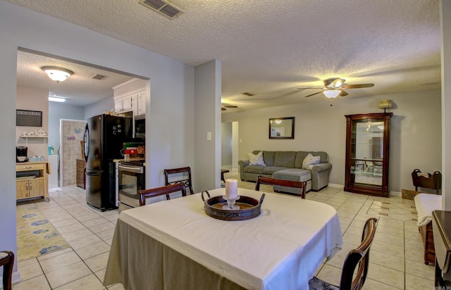 tiled dining space with ceiling fan and a textured ceiling