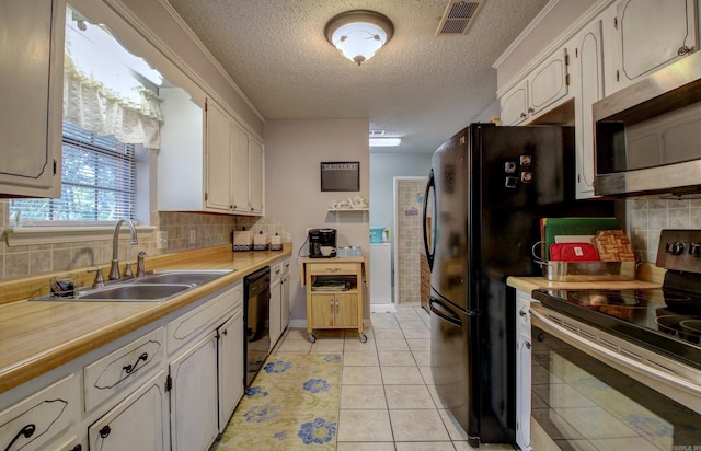 kitchen with white cabinets, light tile patterned floors, sink, tasteful backsplash, and appliances with stainless steel finishes