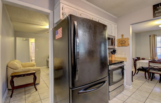 kitchen with light tile patterned flooring, tile counters, white cabinets, appliances with stainless steel finishes, and a textured ceiling