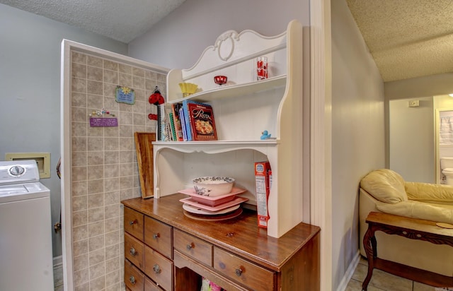 clothes washing area with light tile patterned flooring, washer / dryer, tile walls, and a textured ceiling