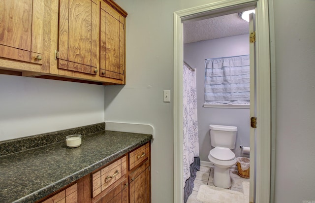 bathroom with tile patterned floors, vanity, a textured ceiling, and toilet