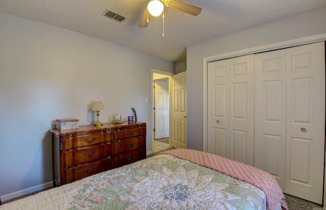 bedroom featuring ceiling fan, light colored carpet, a textured ceiling, and a closet