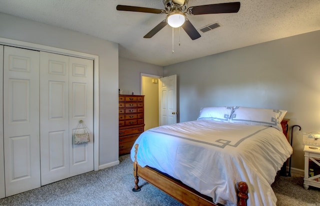 carpeted bedroom with ceiling fan, a closet, and a textured ceiling