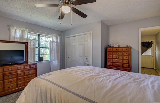 bedroom featuring ceiling fan, a textured ceiling, a closet, and light carpet