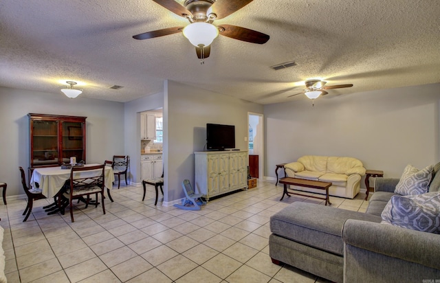 living room featuring ceiling fan, a textured ceiling, and light tile patterned flooring