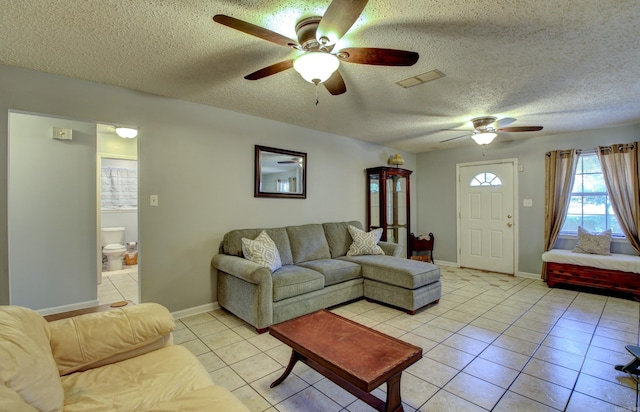 living room with ceiling fan, light tile patterned floors, and a textured ceiling