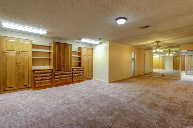 unfurnished living room with a textured ceiling, ceiling fan, and light colored carpet