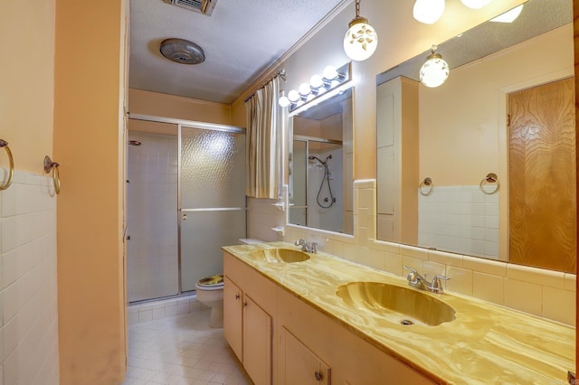 bathroom with vanity, backsplash, an enclosed shower, toilet, and a textured ceiling