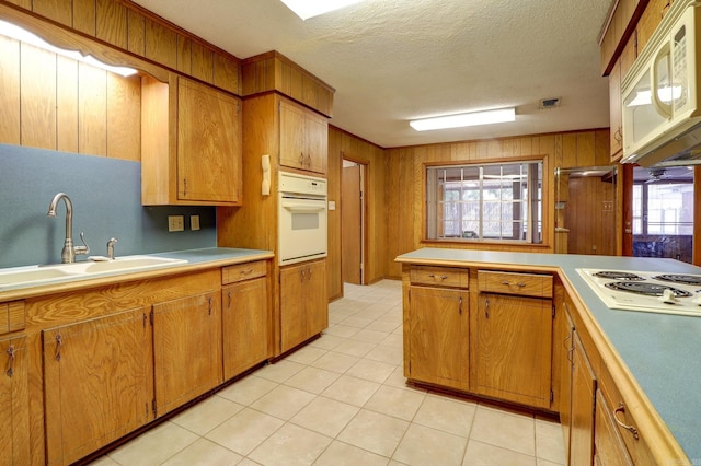 kitchen featuring wooden walls, white appliances, sink, and a textured ceiling