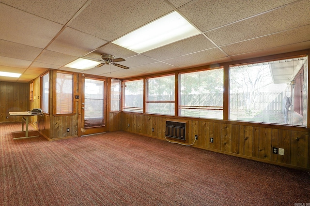 unfurnished sunroom featuring ceiling fan, a drop ceiling, and a wall unit AC