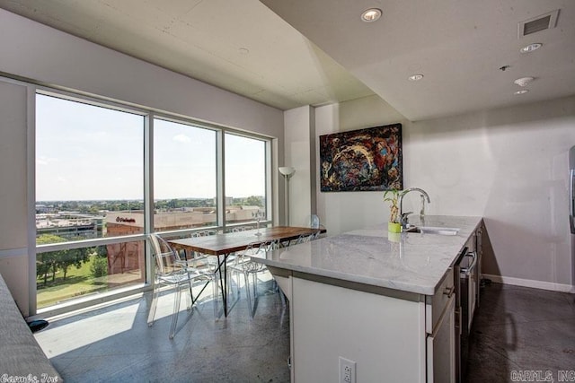 kitchen with kitchen peninsula, light stone counters, and sink