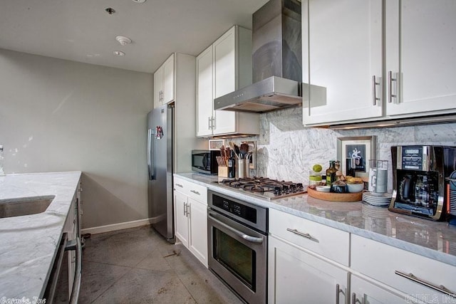 kitchen featuring white cabinets, backsplash, wall chimney range hood, appliances with stainless steel finishes, and light stone countertops