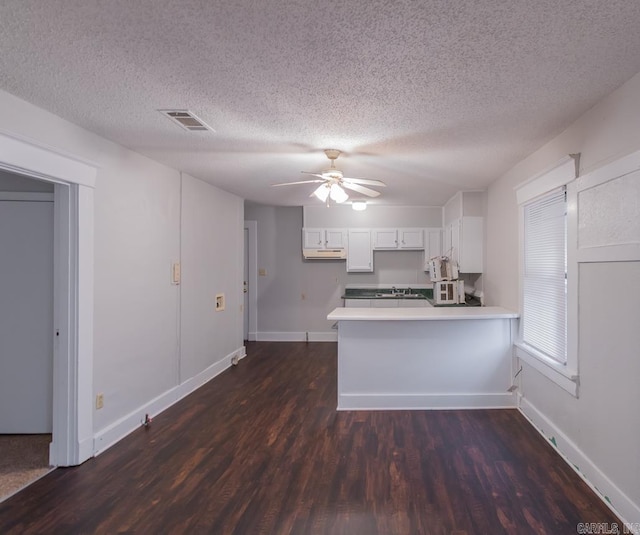 kitchen featuring kitchen peninsula, dark hardwood / wood-style floors, a textured ceiling, and white cabinetry