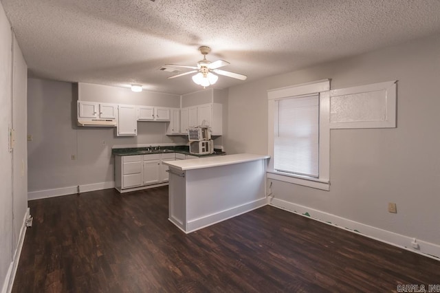 kitchen featuring kitchen peninsula, dark hardwood / wood-style floors, white cabinets, and a textured ceiling