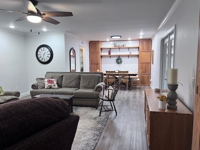 living room featuring crown molding, ceiling fan, and wood-type flooring