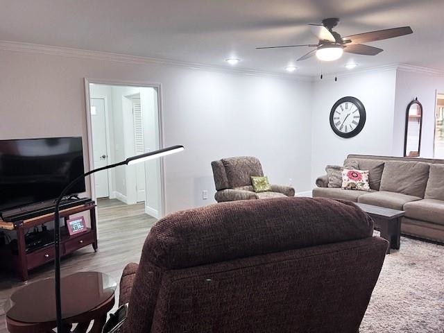 living room featuring crown molding, light wood-type flooring, and ceiling fan