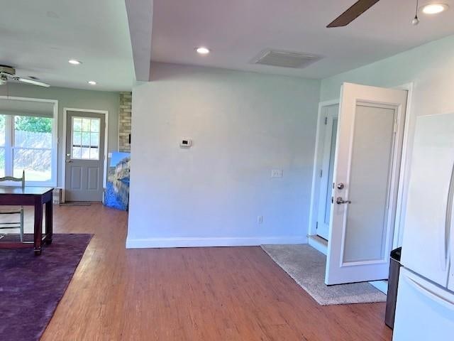 interior space with light wood-type flooring, ceiling fan, and white fridge