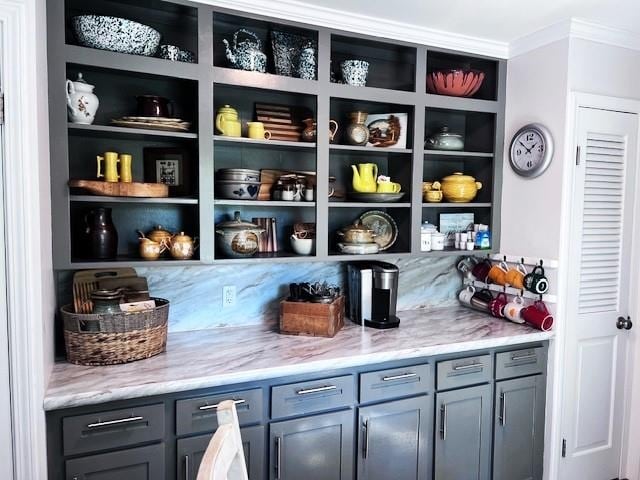 bar with ornamental molding, gray cabinetry, and light stone countertops