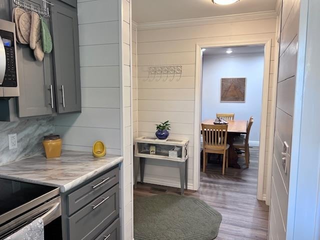 kitchen with wood-type flooring, gray cabinets, ornamental molding, and tasteful backsplash