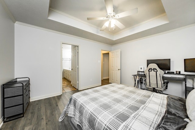 bedroom featuring ceiling fan, a raised ceiling, dark wood-type flooring, connected bathroom, and crown molding