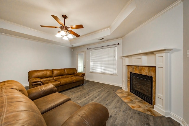 living room with ceiling fan, a raised ceiling, hardwood / wood-style flooring, a fireplace, and crown molding