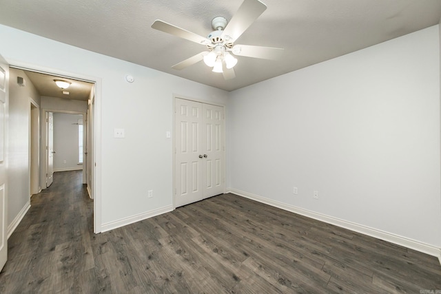 unfurnished bedroom with ceiling fan, dark wood-type flooring, a closet, and a textured ceiling