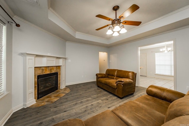 living room with ceiling fan, a raised ceiling, a fireplace, ornamental molding, and hardwood / wood-style flooring