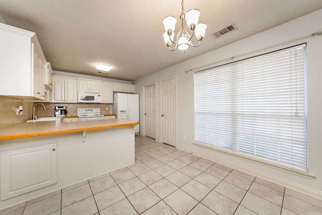 kitchen with pendant lighting, kitchen peninsula, white appliances, white cabinetry, and decorative backsplash