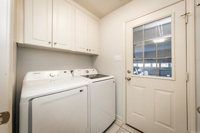 washroom featuring washing machine and dryer, cabinets, and light tile patterned floors