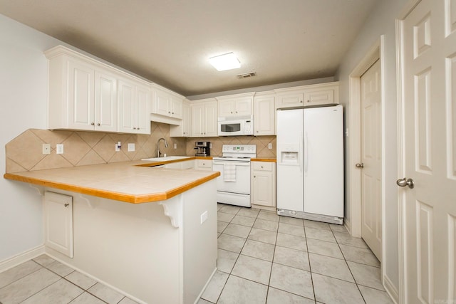 kitchen with tasteful backsplash, white appliances, a breakfast bar area, tile counters, and kitchen peninsula