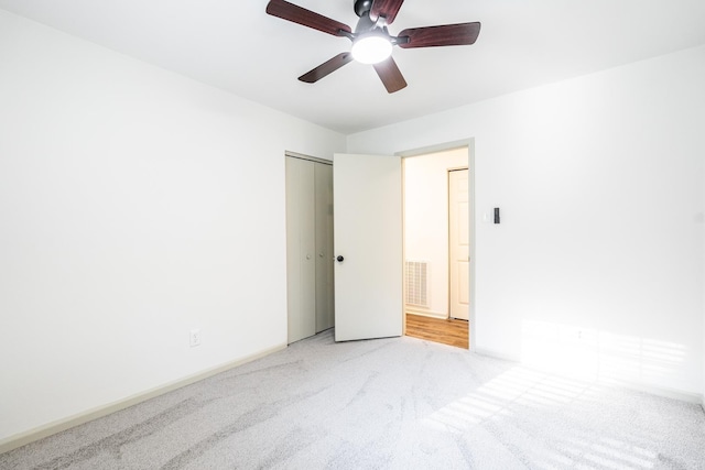 spare room with ceiling fan and light carpet