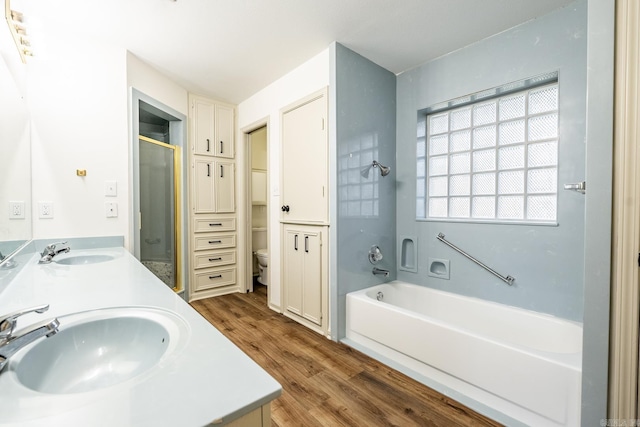 full bathroom with wood-type flooring, shower with separate bathtub, vanity, and toilet