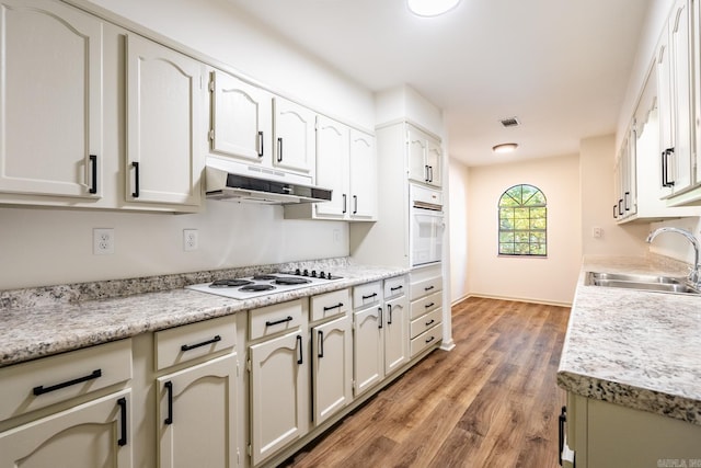 kitchen featuring white cabinets, light hardwood / wood-style floors, sink, and white appliances