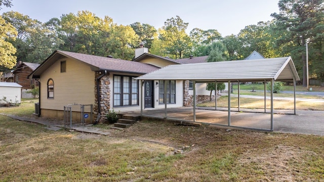 back of house featuring a carport and a lawn